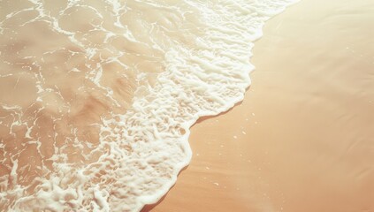 Fototapeta na wymiar Gentle waves wash over a sandy beach in a warm, sunlit aerial view.