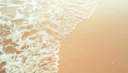Gentle waves wash over a sandy beach in a warm, sunlit aerial view.