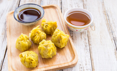 Fresh dumplings with hot steams and tea on wood plate.