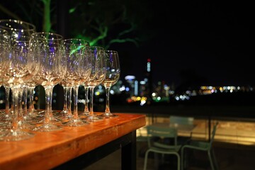 Differential focus.  Foreground wine glasses in focus. Cityscape out of focus in background.  Table...