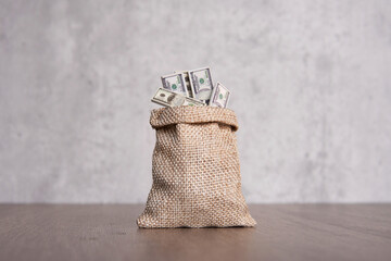 Closeup image of burlap sack overflowing with stacks of U.S. dollar bills with copy space....