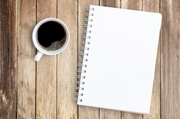 Cup of coffee and notebook on office wood table.