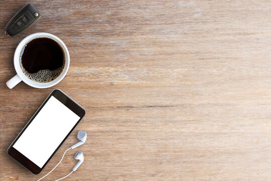 Smart phone,car key and earphone with cup of coffee on wood table