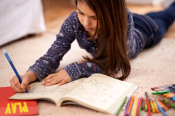 Girl, child and coloring book on floor for drawing in home with learning, development or art in...