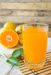 Orange juice with sliced orange on wooden table background