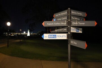 Night time photo of a sign in Kings Park, Perth, showing directions towards the Western Australia State War Memorial, Botanic Garden, and other tourism attractions.
