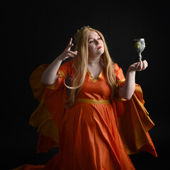 close up portrait of plus sized blonde woman, wearing historical medieval fantasy gown, crowned royal queen.  posing holding wine cup drinking goblet, isolated dark black studio background.
