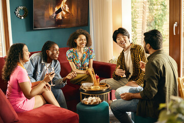 Cheerful young people eating snacks and talking while having weekend home party together - obrazy, fototapety, plakaty