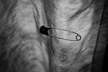 a safety pin attached to a piece of cloth, a safety pin that pierces the cloth