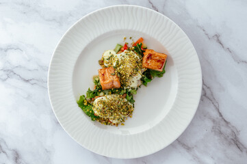 fried salmon fillet with sauce, nuts and vegetables on a plate