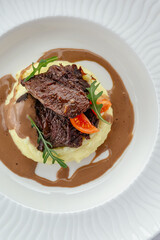 beef tenderloin stewed with herbs in sauce and garnished on a pl