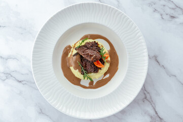 beef tenderloin stewed with herbs in sauce and garnished on a pl