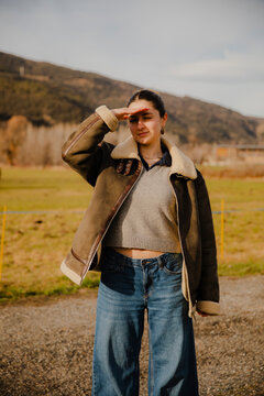 Girl in Jacket and Wide Pants in Mountains looking at camera
