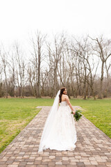 Bride walks on path among bare trees