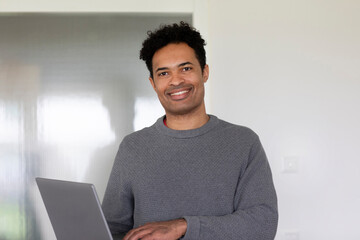 Young man, mixed race, with a laptop in an office