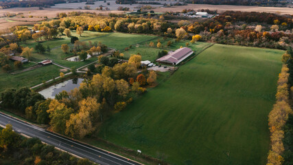 Horse and farm property in fall with barn and pond