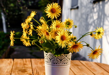 a bouquet of wildflowers in a vase on a wooden table outdoors.