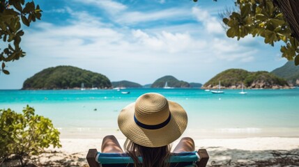 A rear view of a woman in a straw hat relaxing on a chaise longue on the beach, against the background of the sea with ships. Summer Holidays, Travel, Landscape concepts. Horizontal photo, copy space