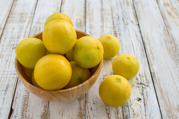 Fresh lemons in a wooden bowl on wooden background