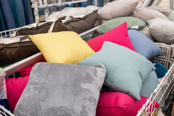 A textile basket filled with a variety of colorful pillows, including electric blue, magenta, and...