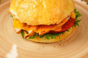 Cheeseburger topped with lettuce and various toppings placed on a plate, ready to be enjoyed.