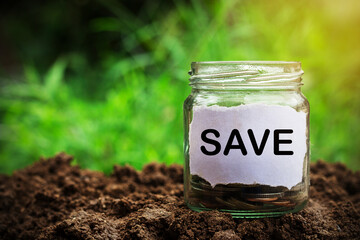 Savings money jar full of coins on soil