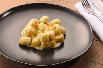 Italian gnocchi with white sauce on black plate
