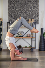 Flexible man performing yoga scorpion pose at home
