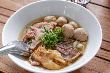beef stew with vegetables. Asian noodle soup with beef meatball with fresh vegetable on wood table vintage style, street food, hot and spicy noodle soup, asian food.