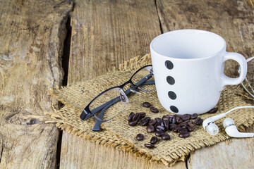 Glasses, earphone,coffee beans and coffee mug on wooden table