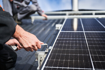 Man engineer mounting photovoltaic solar panels on roof of house. Close up view of technician...