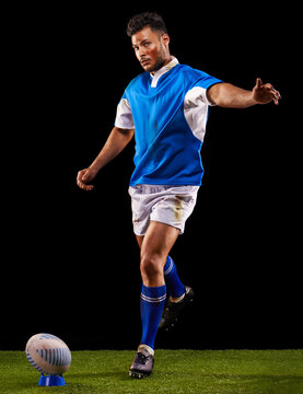 Kick, ball and portrait of man for rugby sport or training for workout, fitness and skill. Person or player on grass and athlete practice for goal or football game or match on black background.
