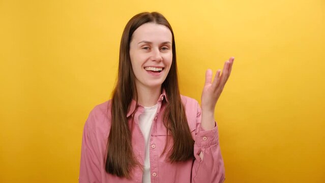 Portrait of emotional young caucasian woman in pink shirt, showing tasty gesture, kisses fingers and says bellissimo, looking at camera, isolated on yellow studio background. Gourmet culinary concept