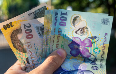 Romanian money hand. Romanian LEI currency, close up. Romanian banknotes of 50, 100 and 200 lei in hand. Making payments, inflation and economic situation concept
