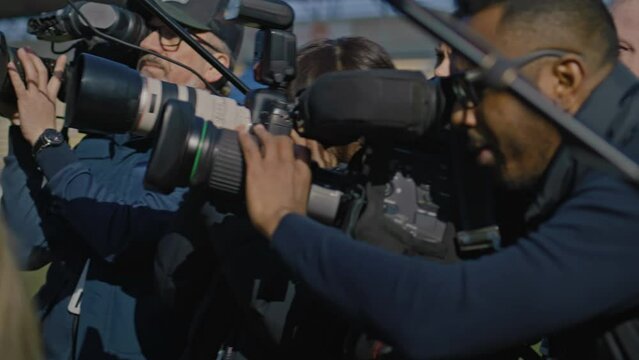 Organization representative answering press questions and giving interview outside a soccer stadium. Interview of private investor at press conference for TV news. Journalists crowd on press campaign.