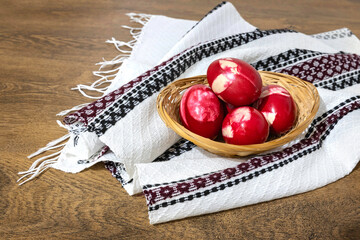 Traditional Romanian red Easter eggs decorated with leaves and boiled in onion peels on a wooden table