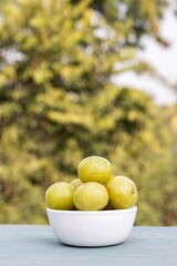 Indian Gooseberry Fruit or Amla Fruit in a White Bowl Isolated on Wooden Table with Copy Space, Also Known as Emblica Myrobalan or Phyllanthus Emblica