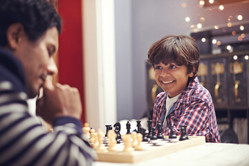 Child, father and smile for chess strategy or planning checkmate move with knight, king or queen. Son, parent and pawn competition learning or decision thoughts or playing, contest or problem solving