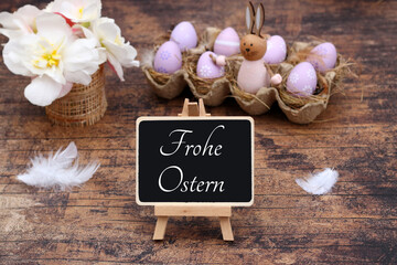 Osterkarte Frohe Ostern. Ein Strauß Blumen mit Ostereiern und Ostergruß auf einer Tafel.	