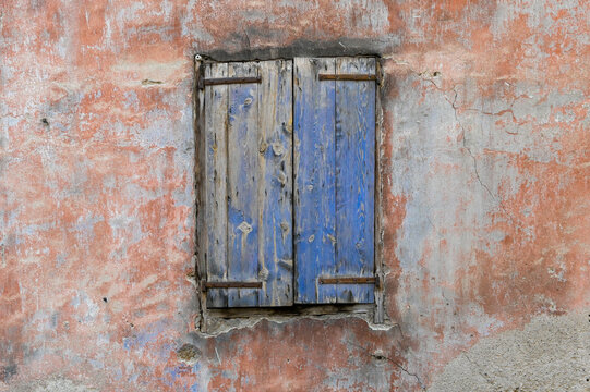 un vieux volet avec de la peinture bleue ecaillée avec un mur ancien ocre provençal