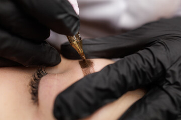 Macro photo introduction of pigment into the skin with a tattoo machine eyebrow correction. Second PMU procedure in a month of permanent eyebrow makeup. Permanent makeup correction.