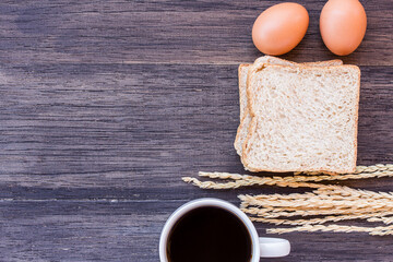 Ears of wheat and cup of coffee on a dark wooden table