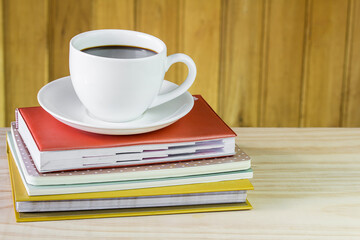 Cup of coffee and book on wooden table