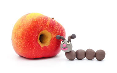 Plasticine caterpillar next to an apple with a hole. - 765508802