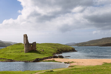 Ruins of Ardvreck Castle rise on a grassy peninsula, caressed by the waters of Loch Assynt in the...