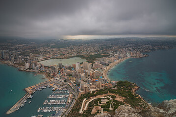 Aerial view of the city of Calpe. The sky is cloudy and the city. You can see the fishing port.