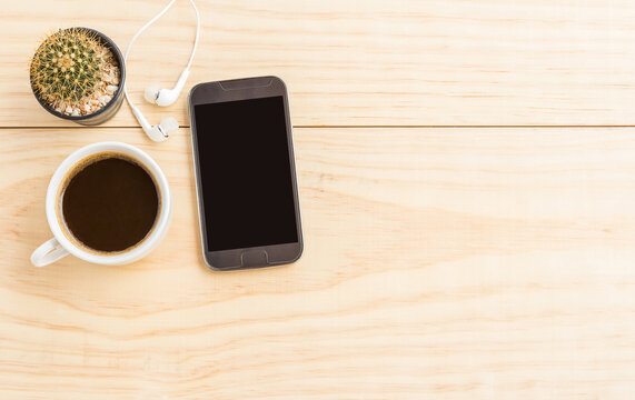 Coffee cup and smartphone on wooden table