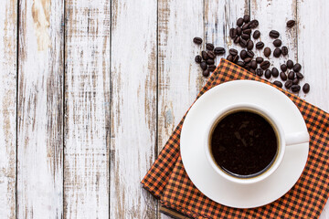 Coffee cup and coffee beans on white wooden table