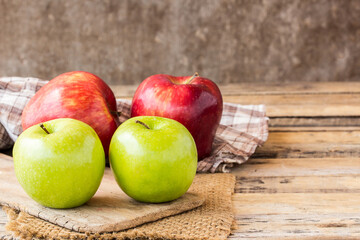 Close up of a red apple and green apple on a wooden table.