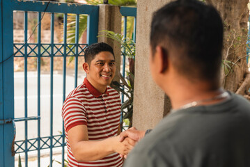 Friendly middle-aged Asian man shaking hands with homeowner outdoors